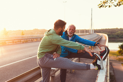 Happy father and son exercising together outdoors on big modern bridge.