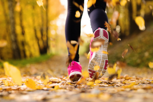 Close up of runner’s feet running in autumn leaves training exercise